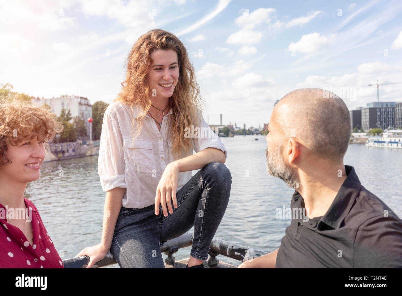 Uomo e donna amici parlando, fiume in background, Berlino, Germania Foto Stock