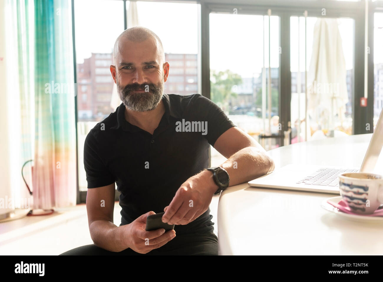 Uomo che utilizza un cellulare in ufficio il giorno di sole Foto Stock
