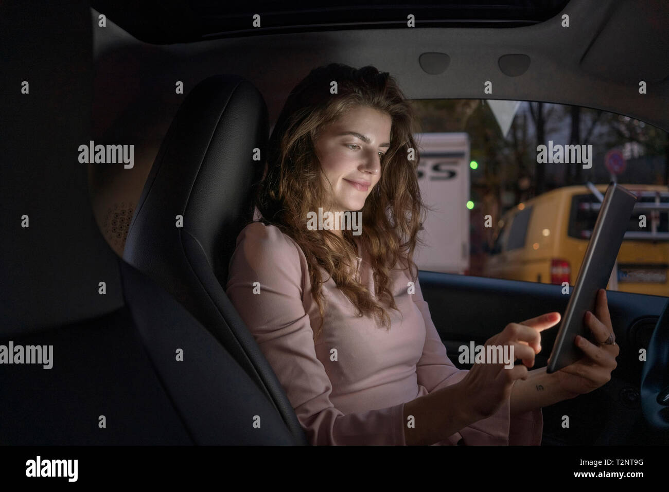 Giovane donna con tavoletta digitale all'interno dell'auto Foto Stock