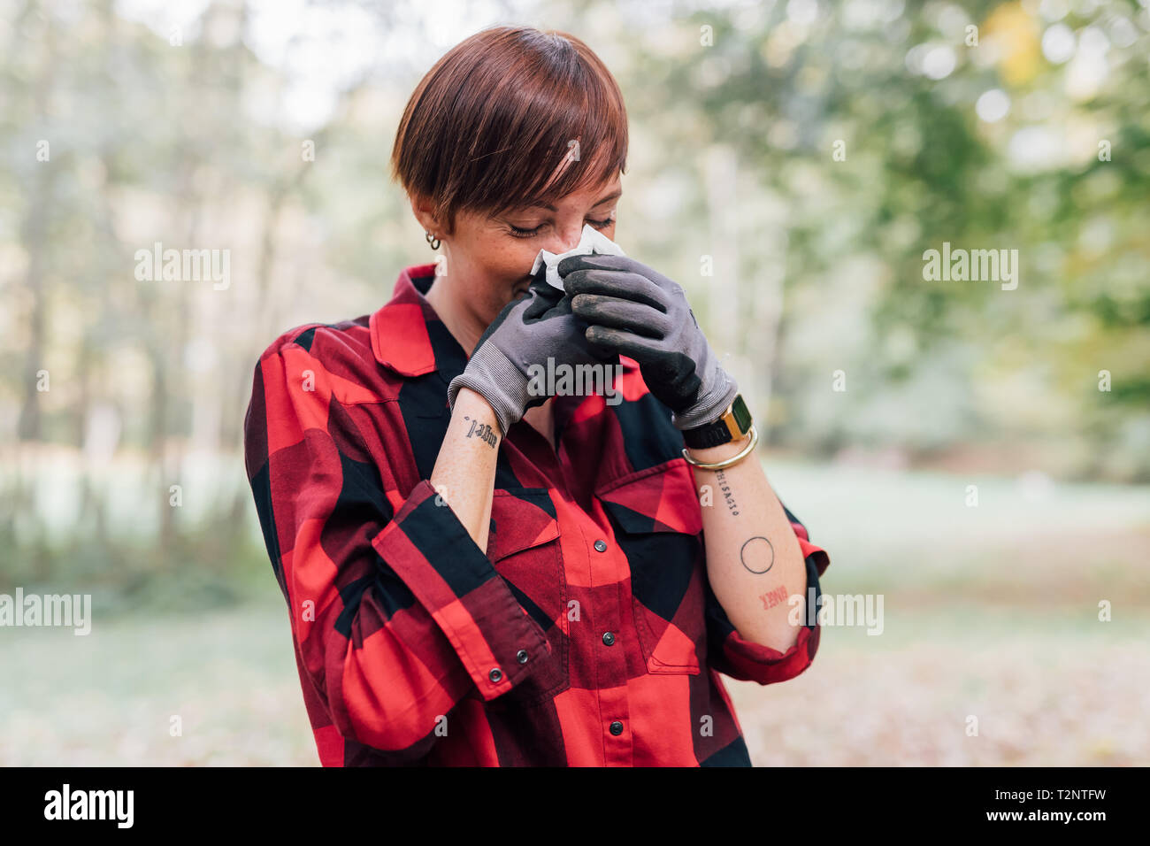 Donna che soffrono di allergia soffia il naso Foto Stock