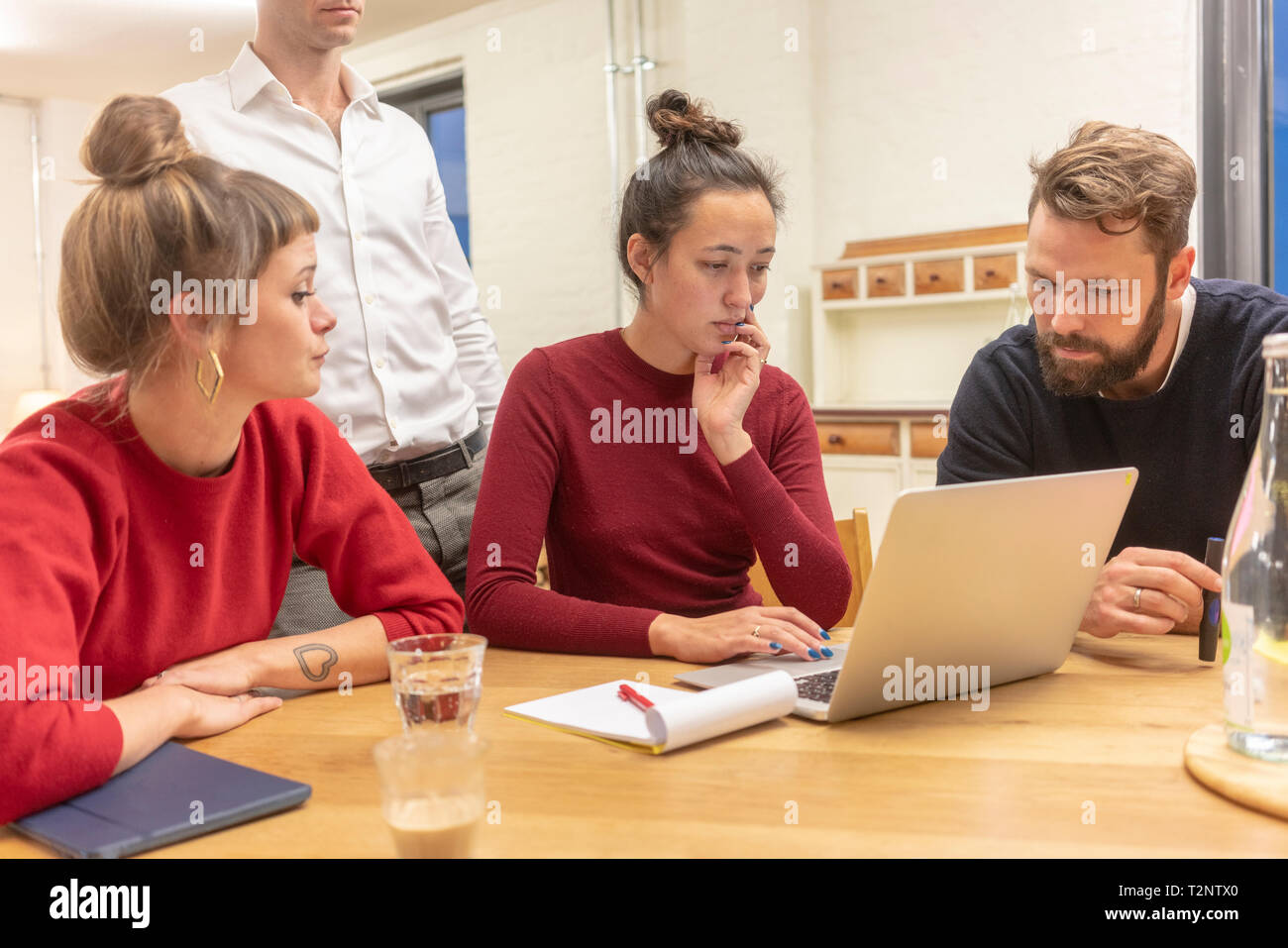 La metà degli adulti team business guardando il portatile a un tavolo per conferenza riunione in ufficio Foto Stock