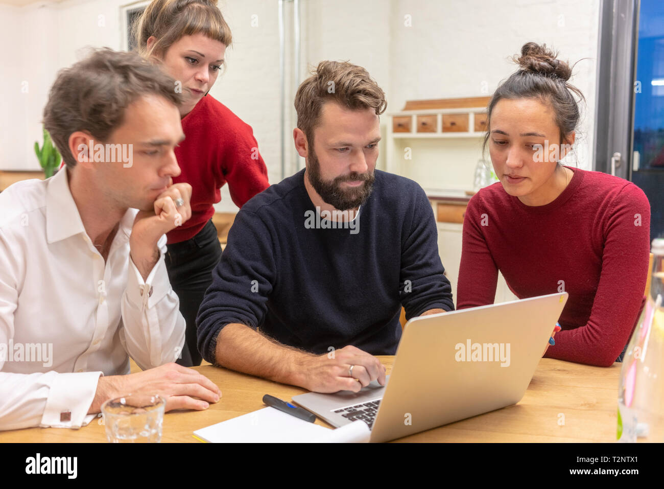 La metà degli adulti team business guardando il portatile a un tavolo per conferenza riunione in ufficio Foto Stock