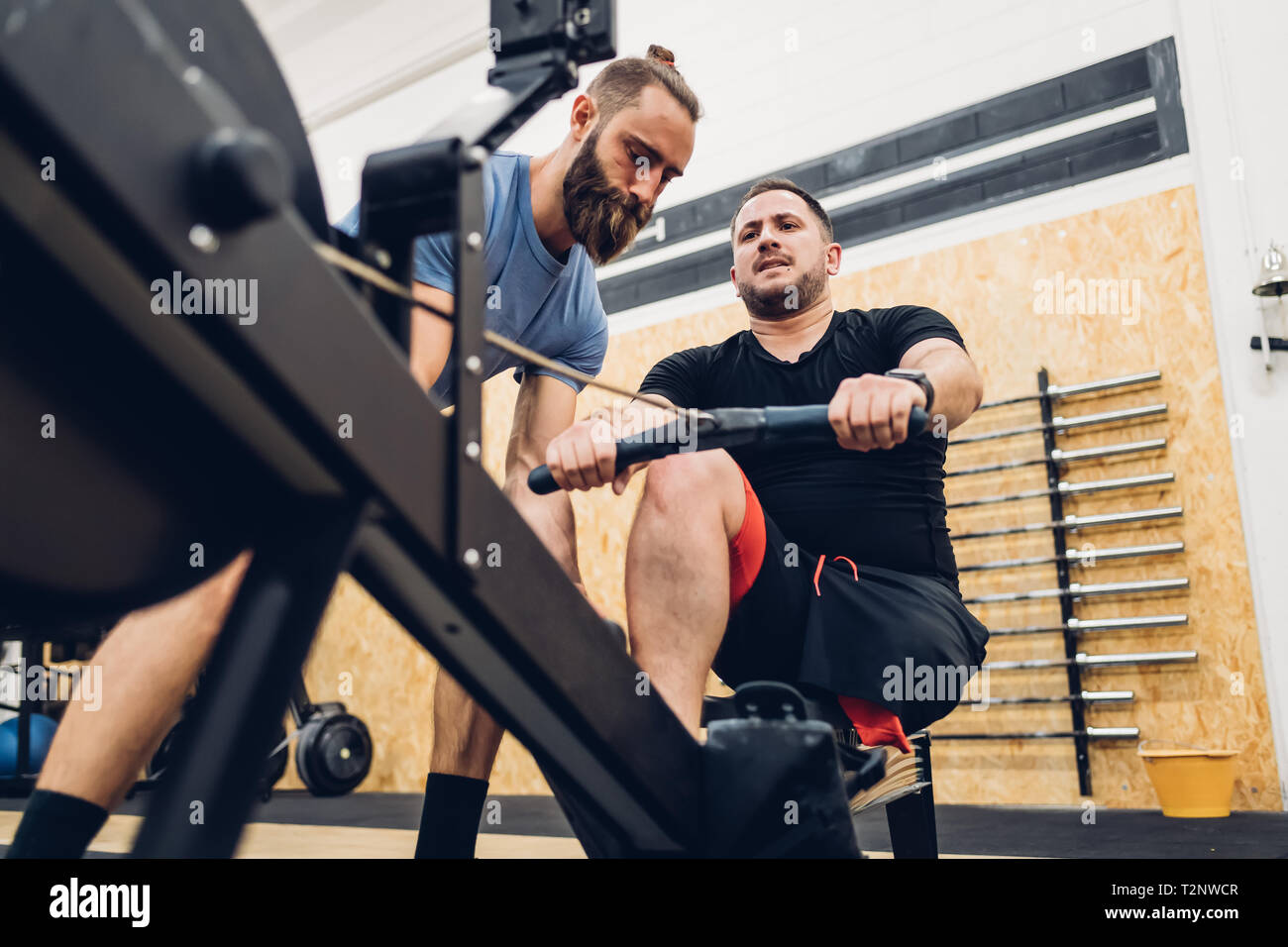 Personal trainer lavora con uomo con disabilità sulla macchina a remi Foto Stock