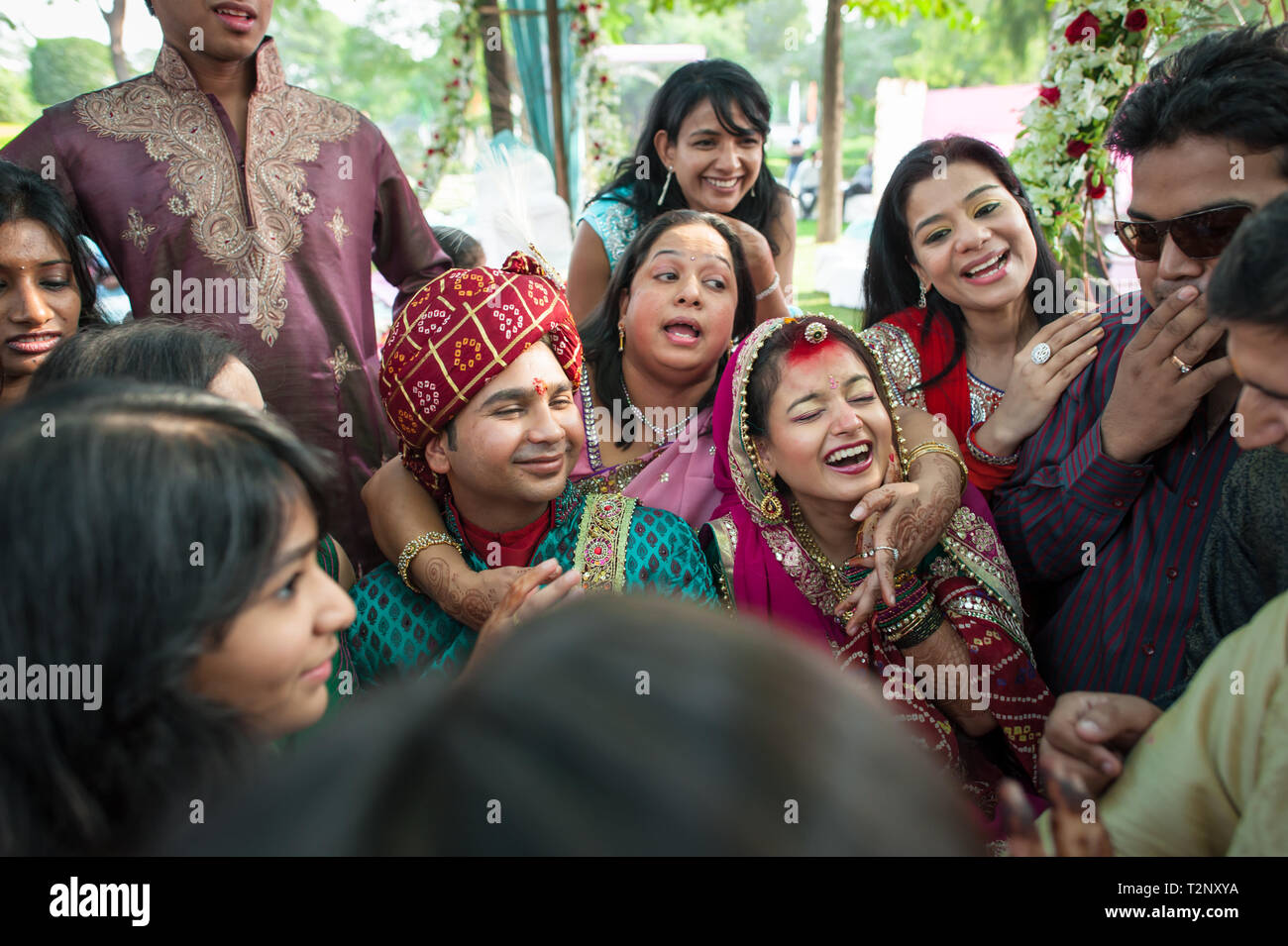 La sposa e lo sposo a un matrimonio indiano, circondato da amici e familiari. Foto Stock
