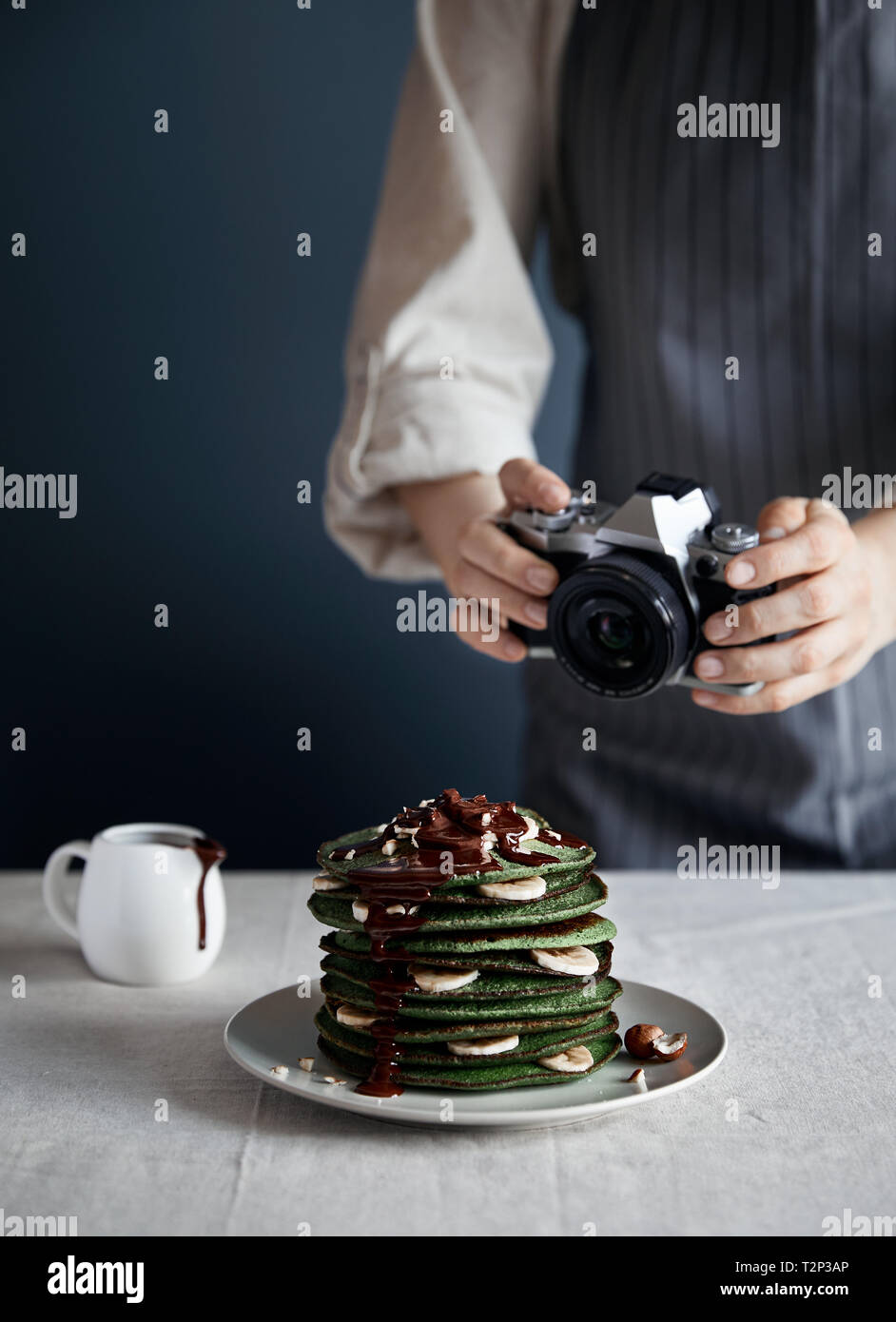 Mamma blogger fotografie verde Pancake fatti in casa con ripieno di spinaci, banana, avena e cioccolato su sfondo grigio Foto Stock