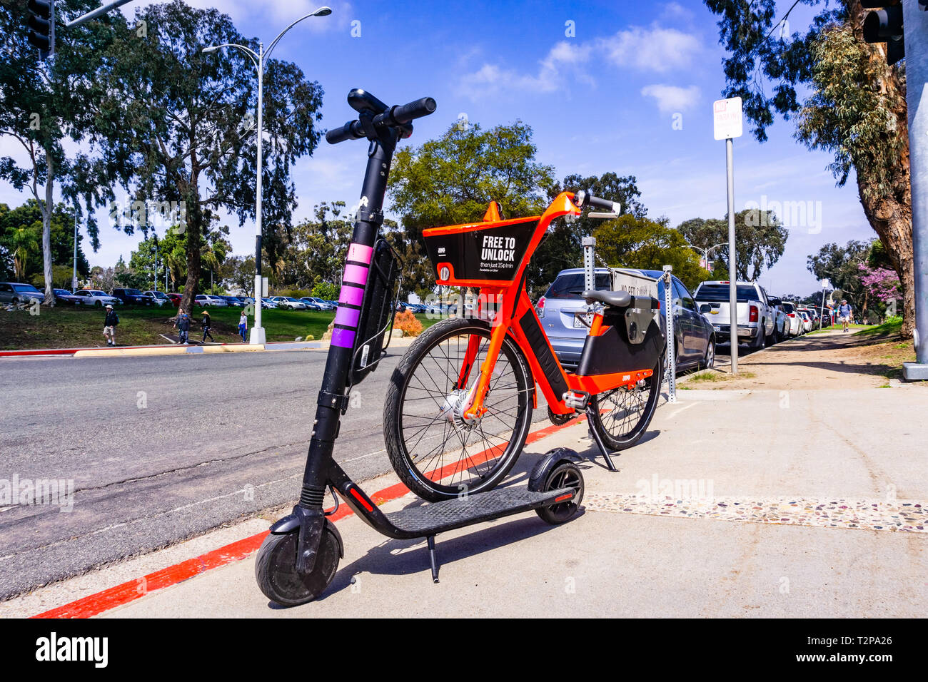 Marzo 19, 2019 San Diego / CA / STATI UNITI D'AMERICA - Salto bicicletta elettrica (di proprietà di Uber) e Lyft Escooter parcheggiato a fianco a fianco sul marciapiede, vicino parcheggiata vicino Balbo Foto Stock