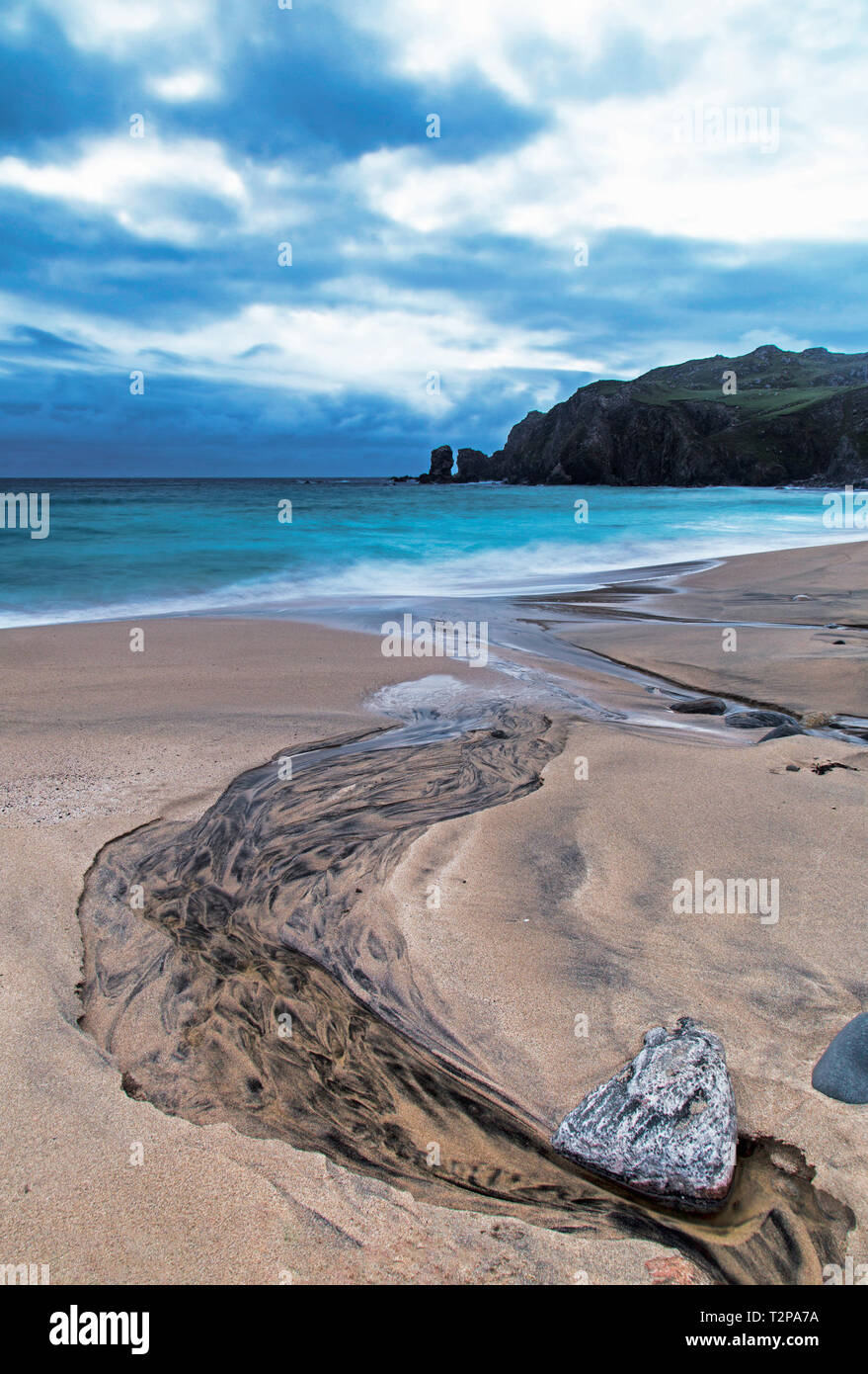 Il fiume nero corre giù a Dalmore beach sull'isola di Lewis Foto Stock