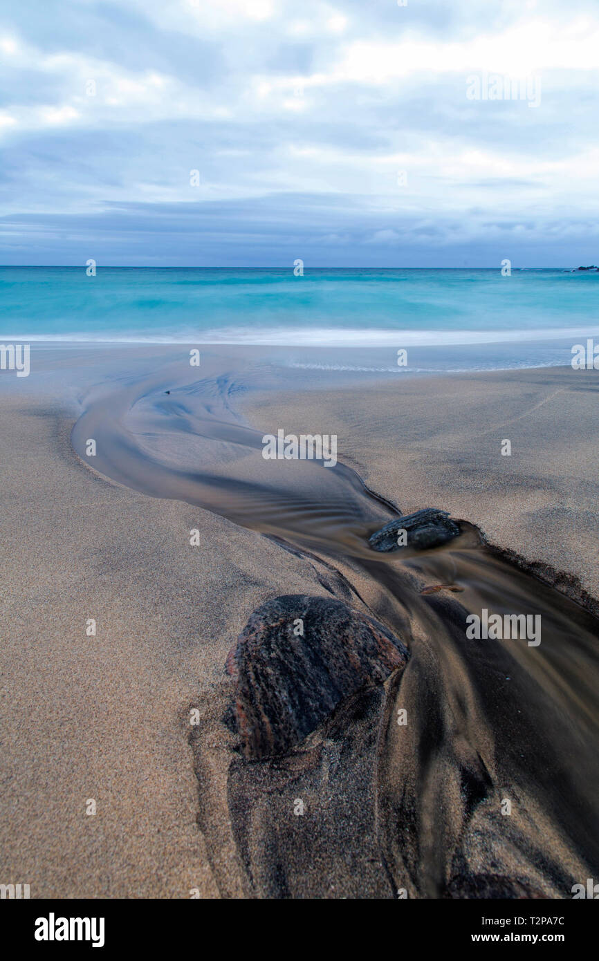 Il fiume nero corre giù a Dalmore beach sull'isola di Lewis Foto Stock