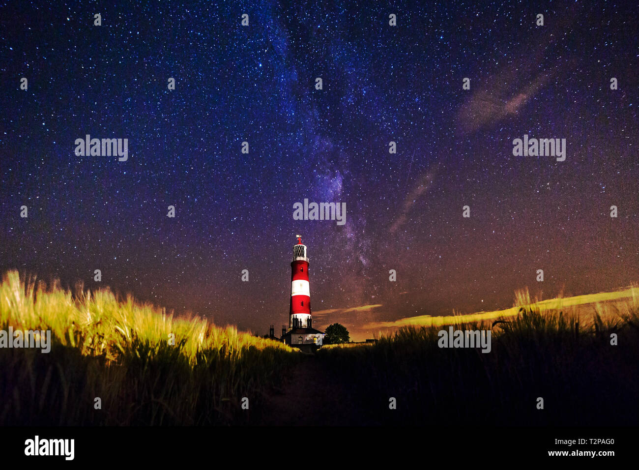 Happisburgh, Norfolk, Regno Unito, 28 Luglio 2016 - Mostra Happisburgh lighthouse di notte con la via lattea sulla Costa North Norfolk, utilizzata per illuminare il cl Foto Stock