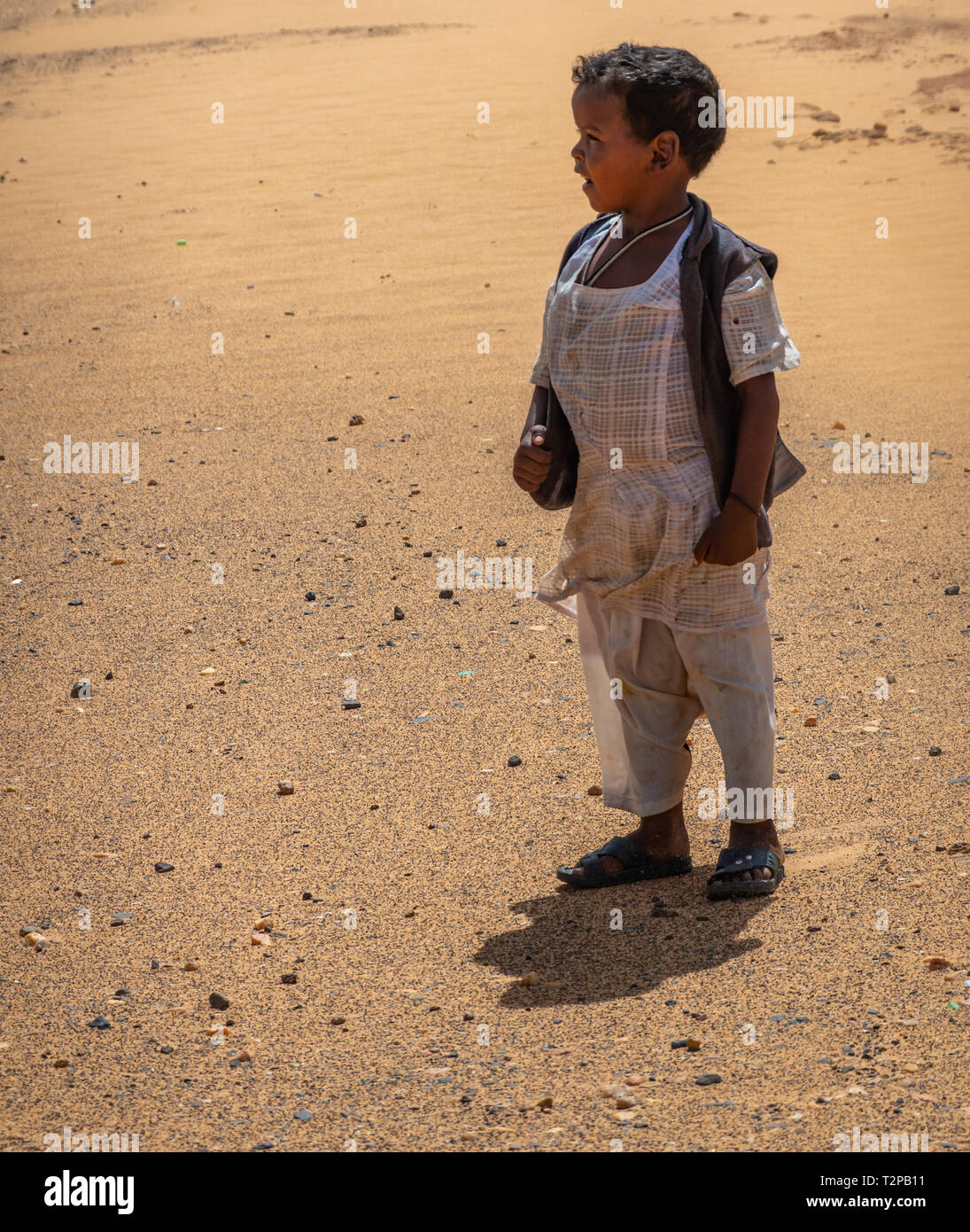 Kerma, Sudan, Febbraio 7, 2019: piccoli sudanesi colorato ragazzo con i  capelli neri, bianchi pantaloni e camicia bianca e blu scuro vest guardando  lateralmente oltre il des Foto stock - Alamy