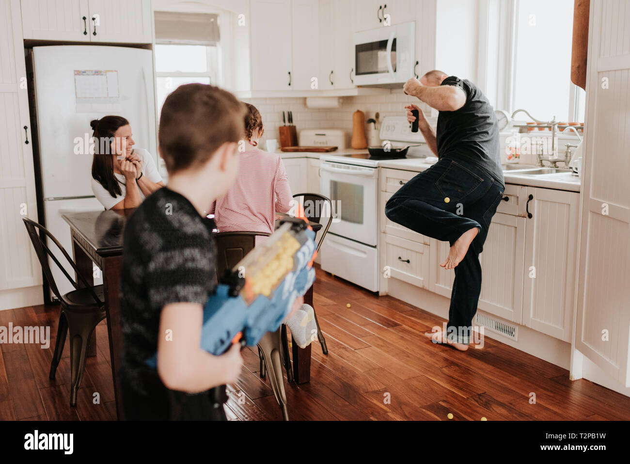 Ragazzo padre di tiro con palla Schiuma pistola in cucina Foto Stock