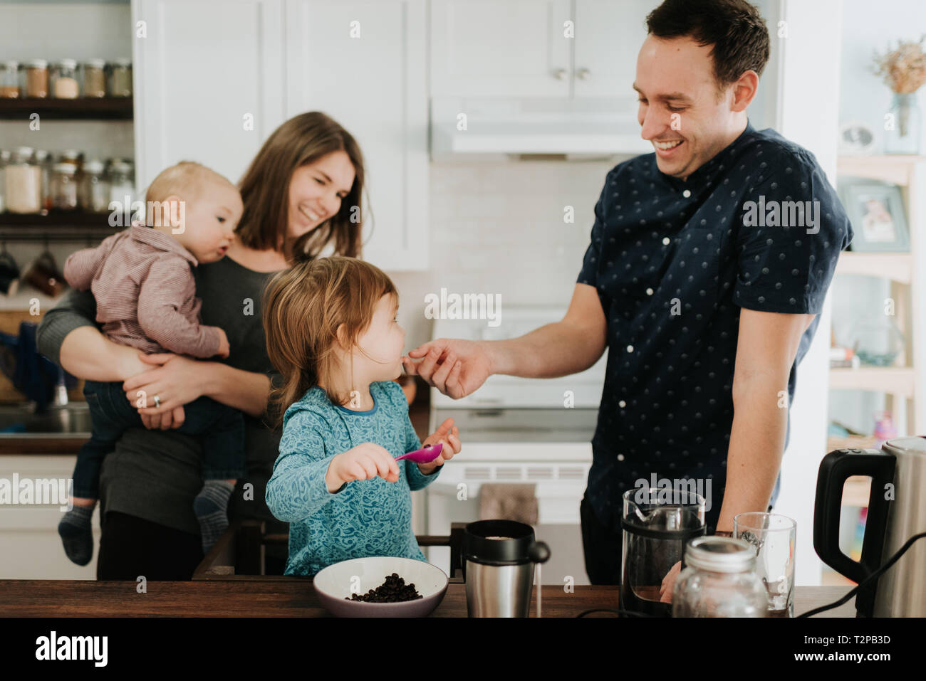 Metà adulto giovane con bambino la figlia e il figlio neonato al tavolo della cucina Foto Stock