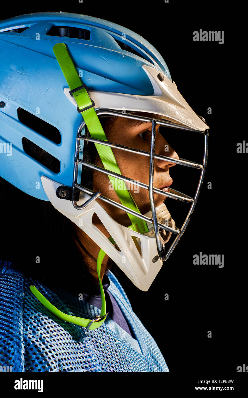 Giovane maschio lacrosse player in lacrosse Casco, close up ritratto su sfondo nero Foto Stock