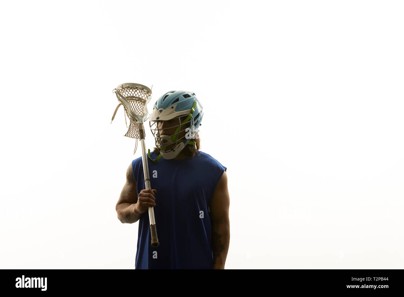 Giovane maschio lacrosse giocatore porta lacrosse stick sulla sua spalla, ritratto contro uno sfondo bianco Foto Stock