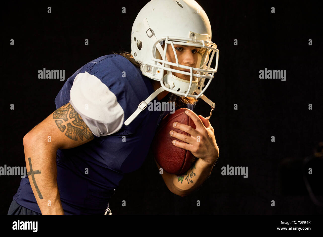 Ritratto di quarterback con calcio, sfondo nero Foto Stock
