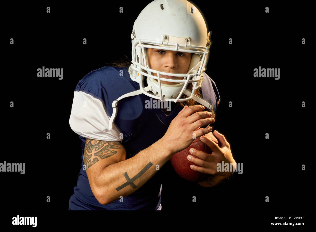 Ritratto di quarterback con calcio, sfondo nero Foto Stock