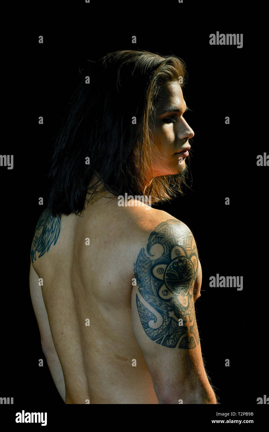 Ritratto di giovane uomo con tatuaggio sul braccio, sfondo nero Foto Stock