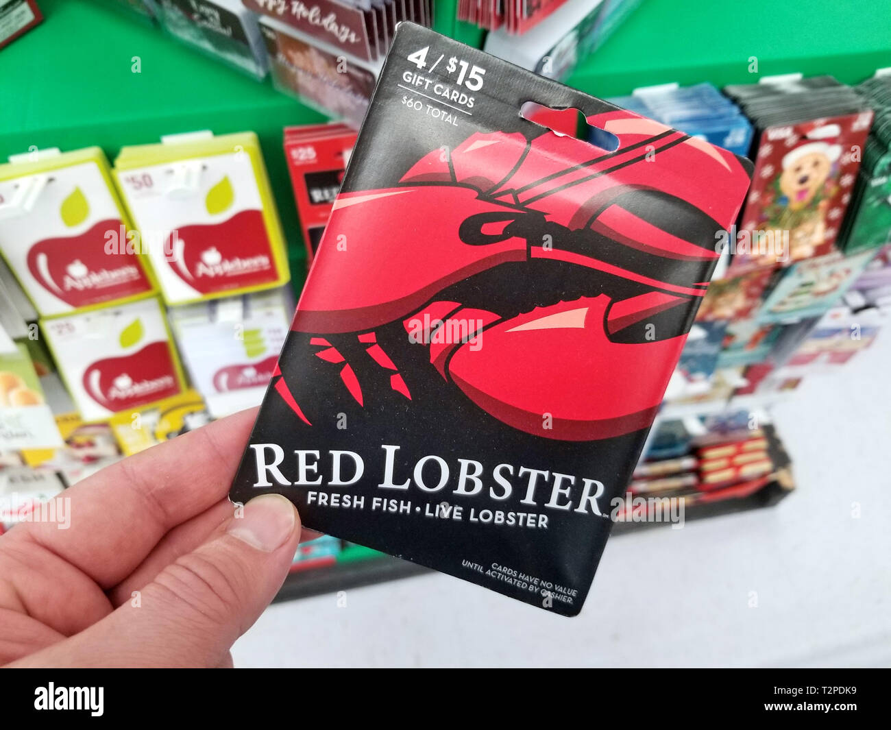 PLATTSBURGH, Stati Uniti d'America - 21 gennaio 2019 : Rosso aragoste gift card in una mano sopra un ripiani con diverse carte regalo in un Walmart store. Foto Stock