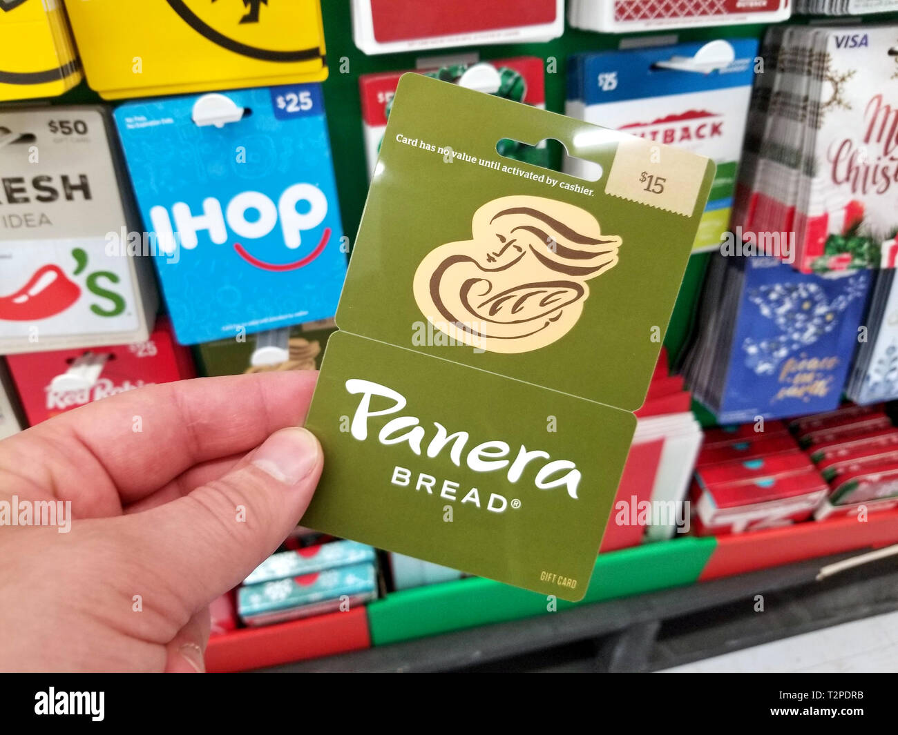 PLATTSBURGH, Stati Uniti d'America - 21 gennaio 2019 : Panera Bread gift card in una mano sopra un ripiani con diverse carte regalo in un Walmart store. Foto Stock
