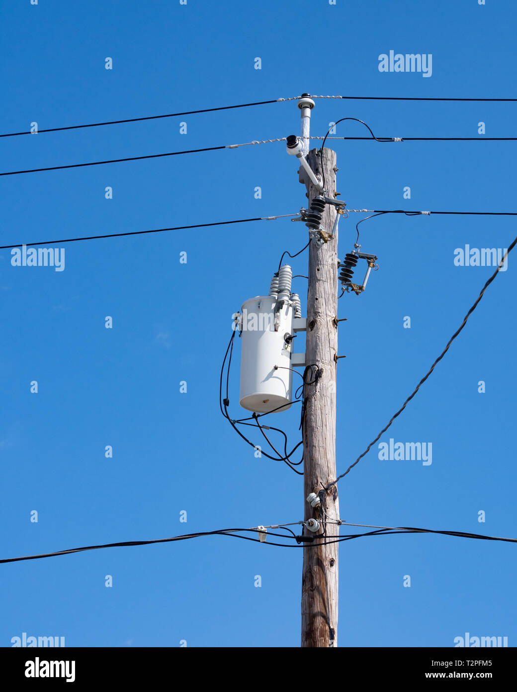 Un trasformatore elettrico e cavi di trasmissione, TV via cavo e telefono i  fili elettrici collegati a un vecchio legno polo di potenza con un profondo  cielo blu sullo sfondo Foto stock -