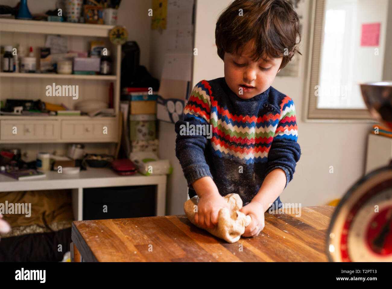 Il Toddler lavorazione dell'impasto sul piano di lavoro della cucina Foto Stock