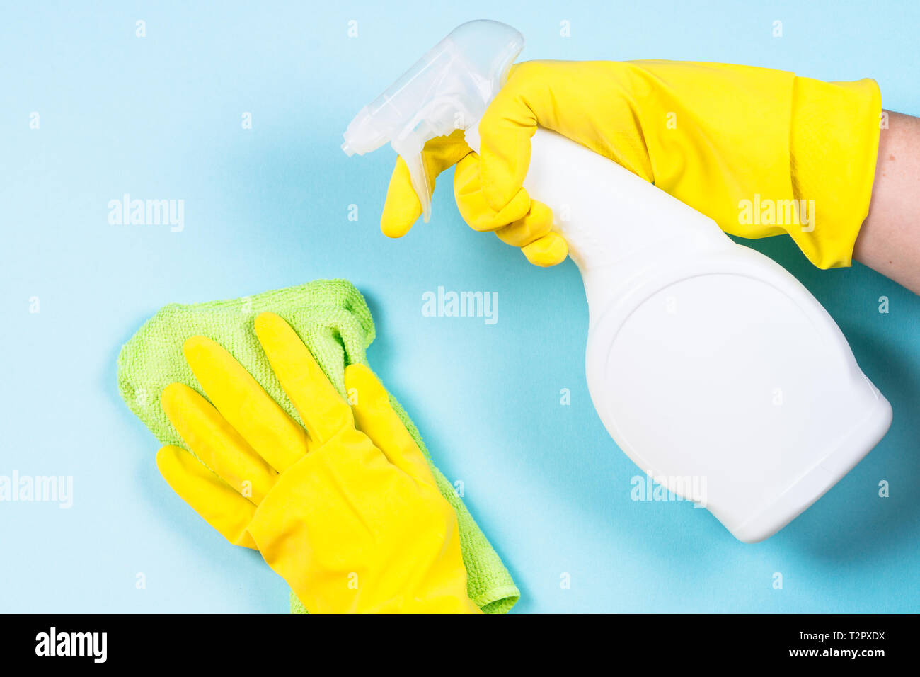 Donna di pulizia parete blu con il panno in microfibra e spray per la pulizia di agente. Foto Stock