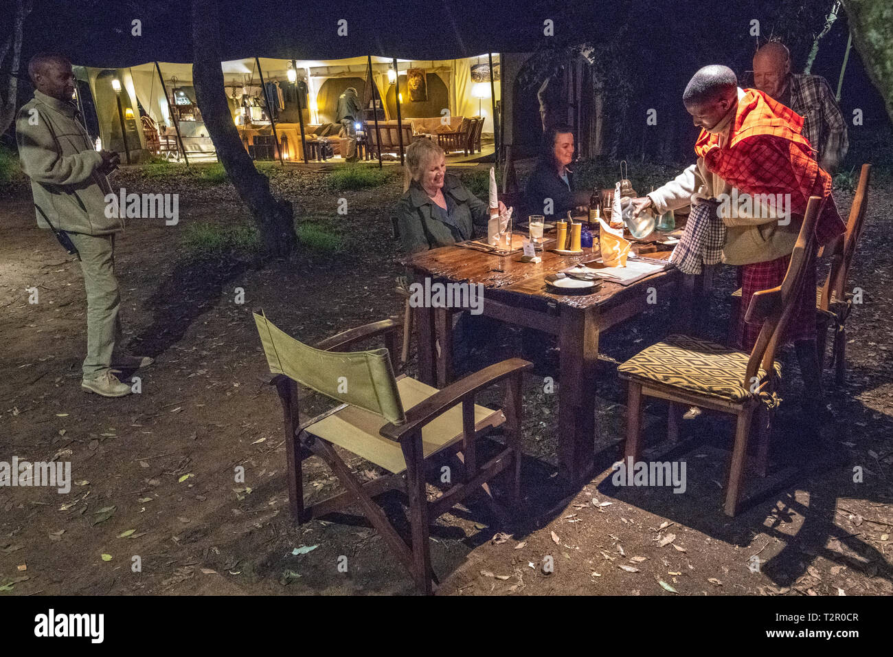 Le persone si radunano per un pasto all'aperto ad alta fine campeggio nel Masai Mara National Reserve, Kenya Foto Stock