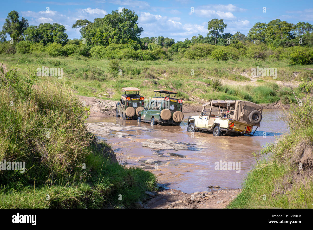 Gioco di spettatori che trasportano unità turistica attraverso un flusso nel Masai Mara National Reserve, Kenya Foto Stock