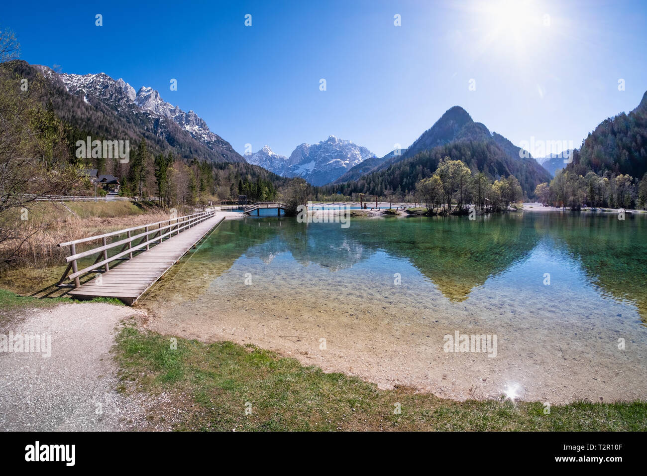 Ponte sopra il lago di Jasna con montagne e un rasoio Prisojnik sul horizont in Slovenia Foto Stock