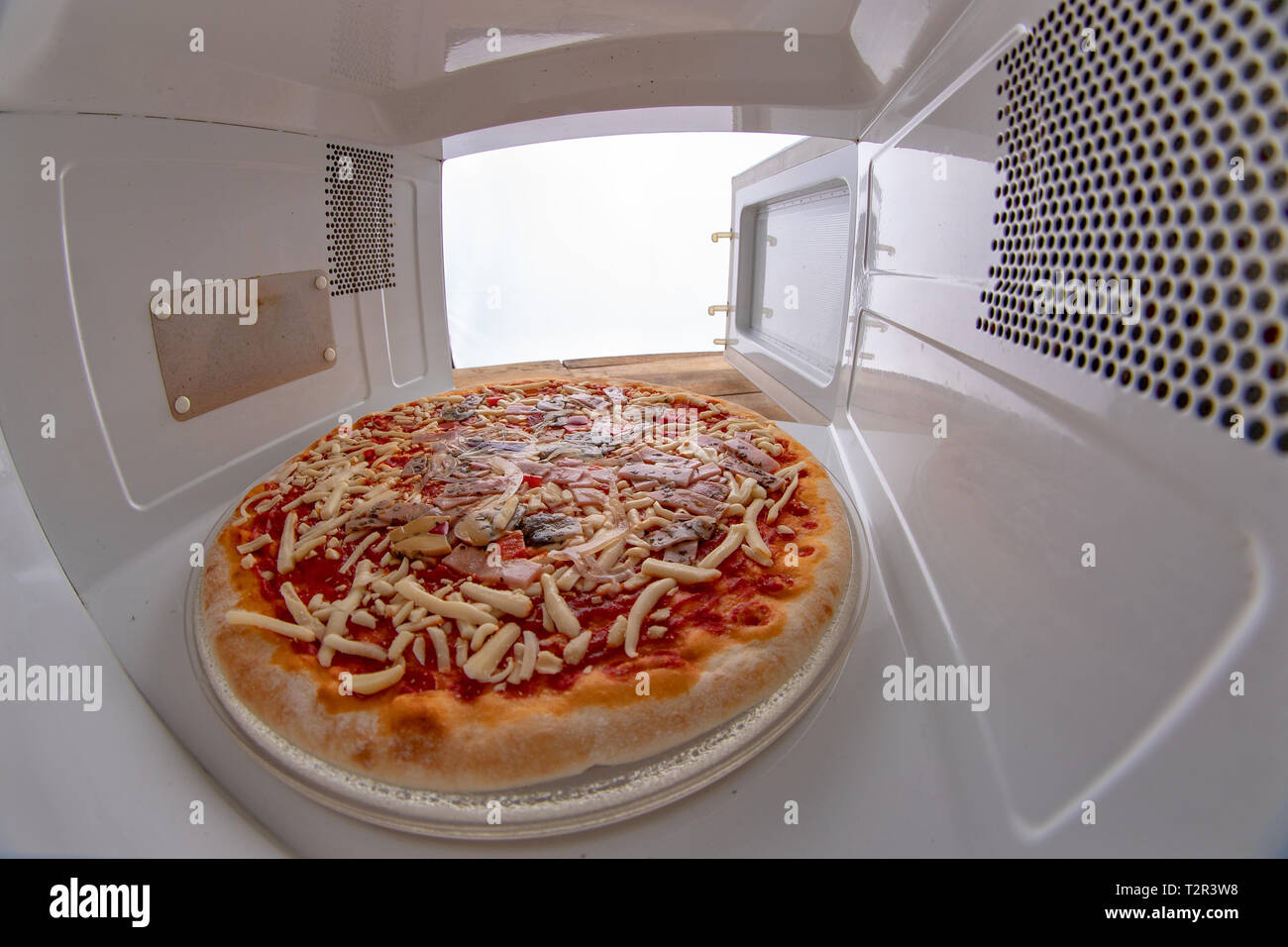 La pizza dal supermercato nel forno a microonde. Il fast food preparate  nella cucina domestica. Sfondo chiaro Foto stock - Alamy