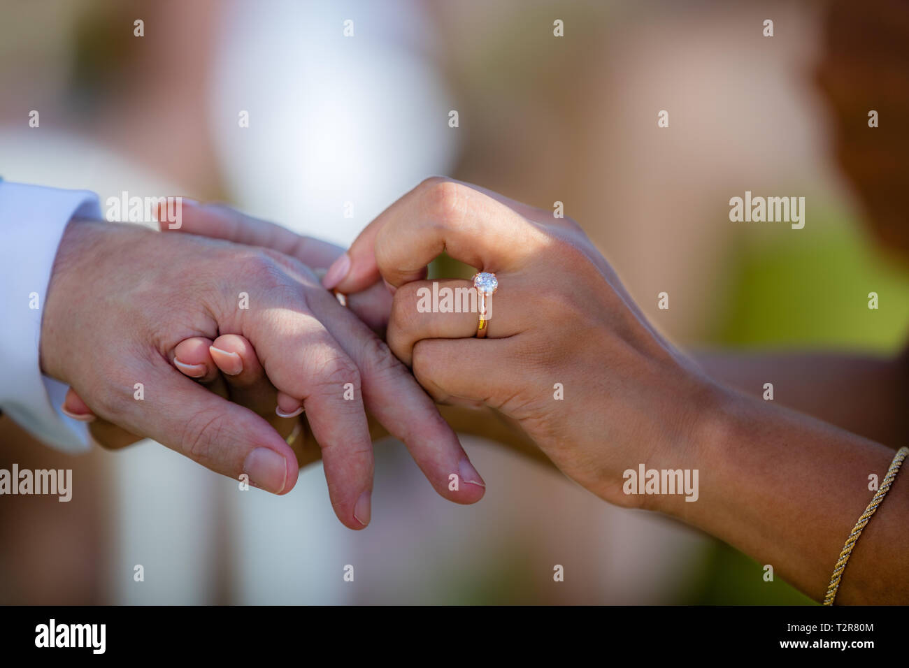 Sposa mettendo un dorato anello di nozze sposi sul dito. Il meticciato - uomo caucasico e donna asiatica. Foto Stock
