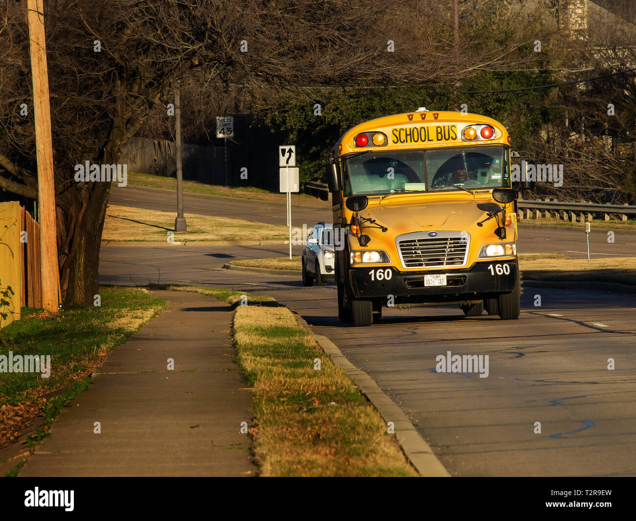 Public School bus proviene da un piccolo grado su una mattina di sole, assicurandosi che i bambini arrivare a scuola in orario Foto Stock
