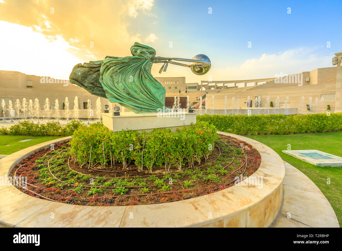 Doha, Qatar - 22 Febbraio 2019: la forza della natura scultura con fontane danzanti e Katara Anfiteatro al tramonto sullo sfondo. Katara Vil culturale Foto Stock