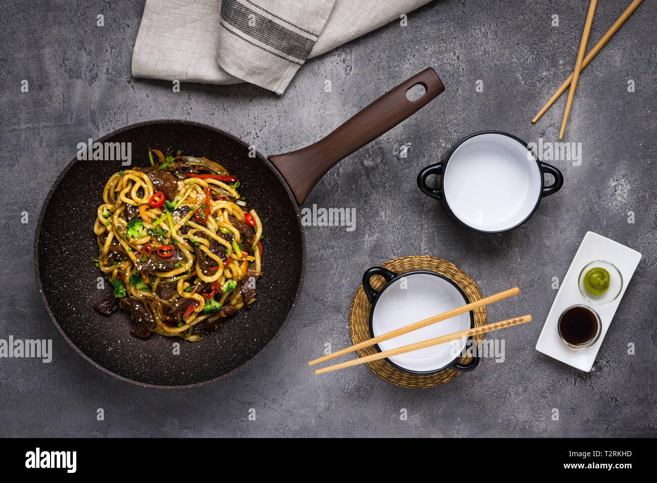 Udon Stir-Fry Tagliatelle con manzo e verdure in padella Wok su sfondo scuro Foto Stock
