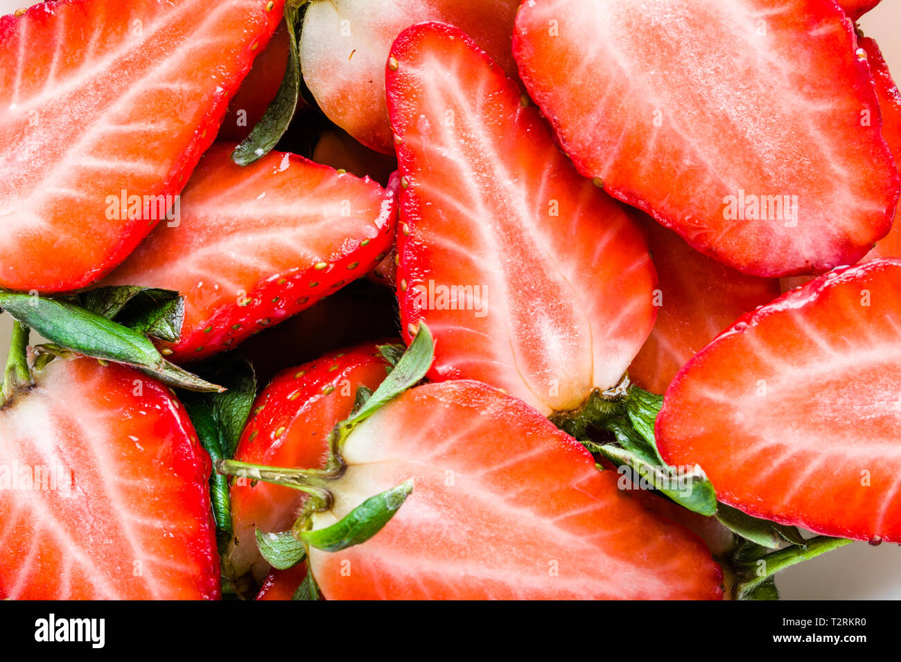 Fragole fresche a fette, texture, sfondo rosso Foto Stock