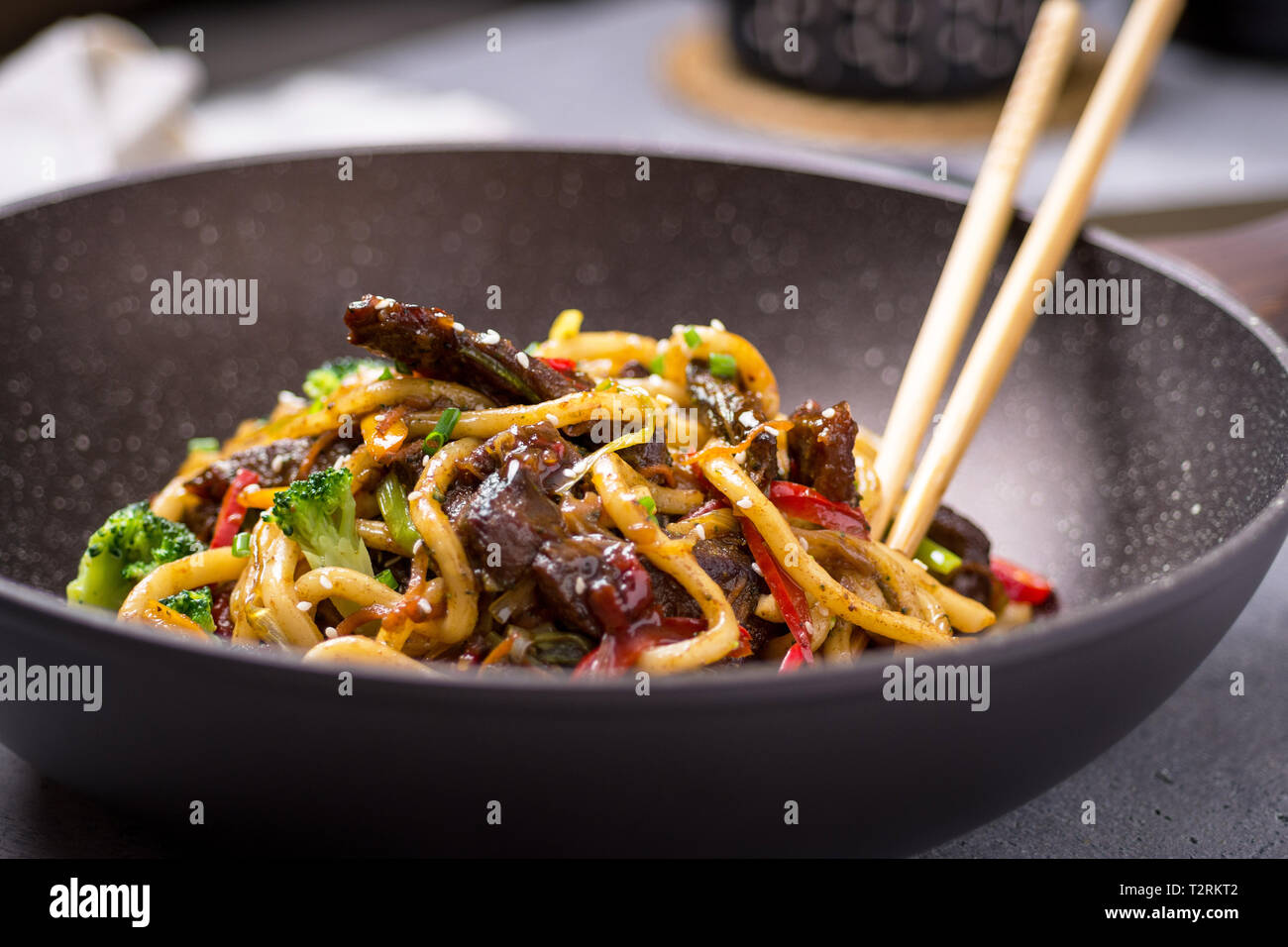 Udon Stir-Fry Tagliatelle con manzo e verdure in padella Wok su sfondo scuro Foto Stock