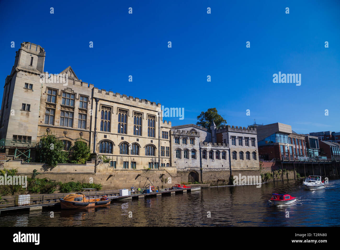 York, North Yorkshire. Barche ormeggiate accanto a un grande vecchio edificio accanto al fiume Ouse. Foto Stock