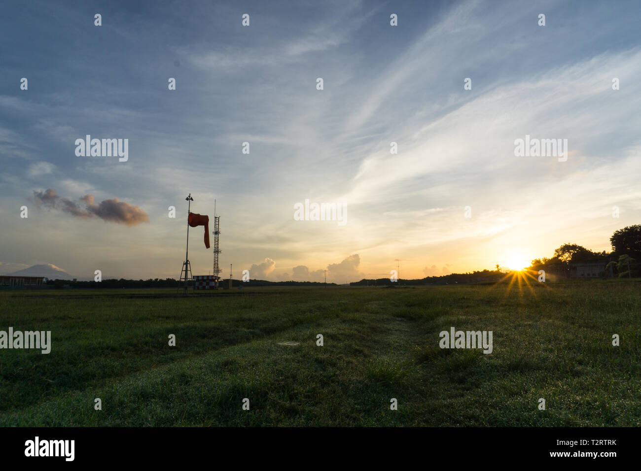Sunrise all'aeroporto di Bali. Mattina vibes dal luminoso cielo chiaro. Aspetto di erba verde e guardare il calzino di vento, il vento è calmo Foto Stock