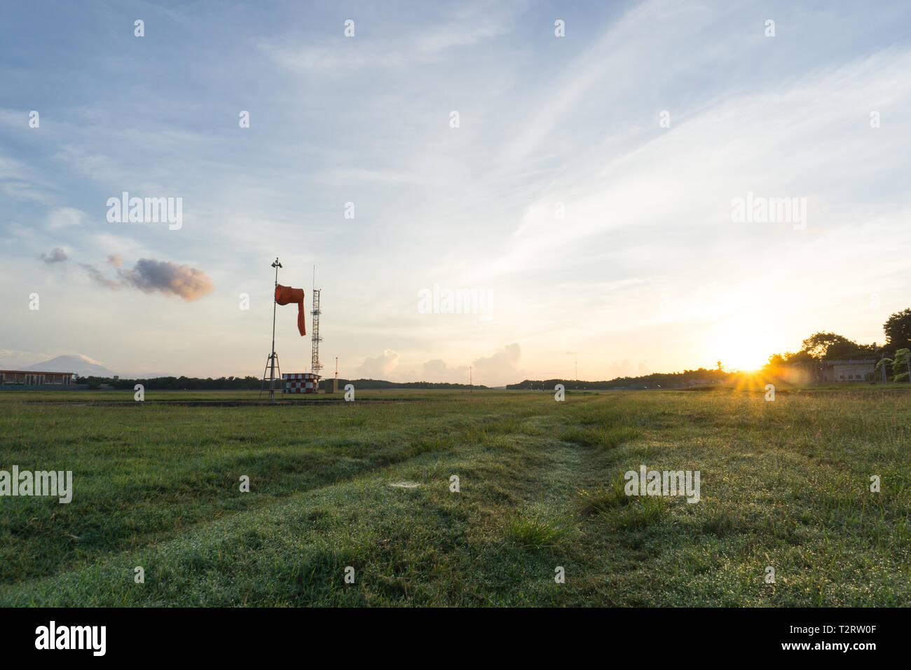 Sunrise all'aeroporto di Bali. Mattina vibes dal luminoso cielo chiaro. Aspetto di erba verde e guardare il calzino di vento, il vento è calmo Foto Stock