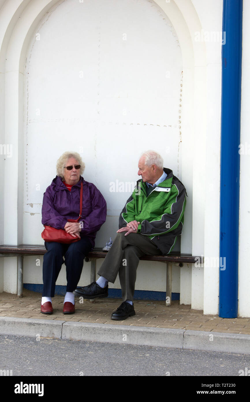 Una coppia di pensionati anziana coppia avente una conversazione seduti insieme. Foto Stock