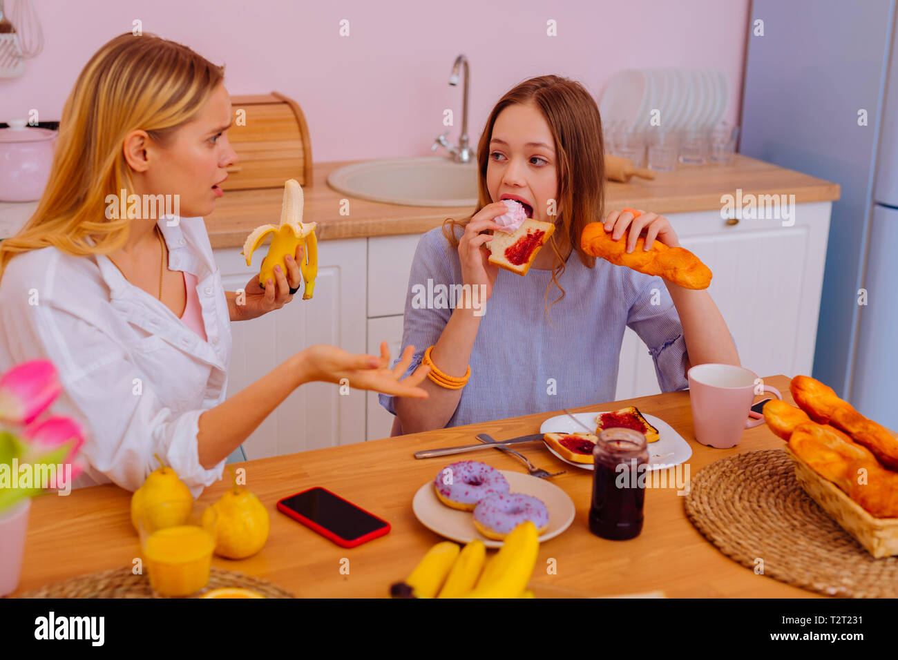 Alimenti zuccherati. La sorella maggiore sensazione scioccato di vedere la sua sorella più giovane di mangiare troppo cibo zuccherati Foto Stock