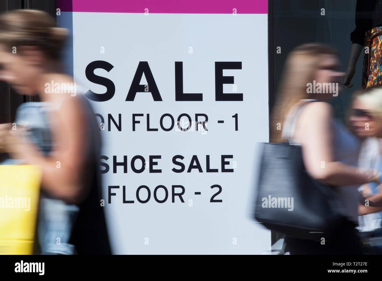 Pedoni camminare davanti a un segno di vendita Foto Stock