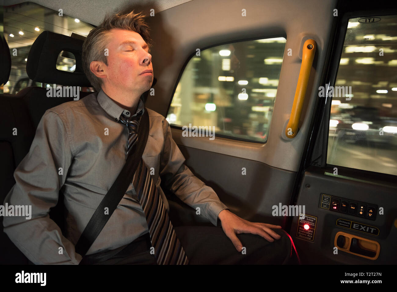 Imprenditore caucasico addormentato nel retro di un taxi Foto Stock