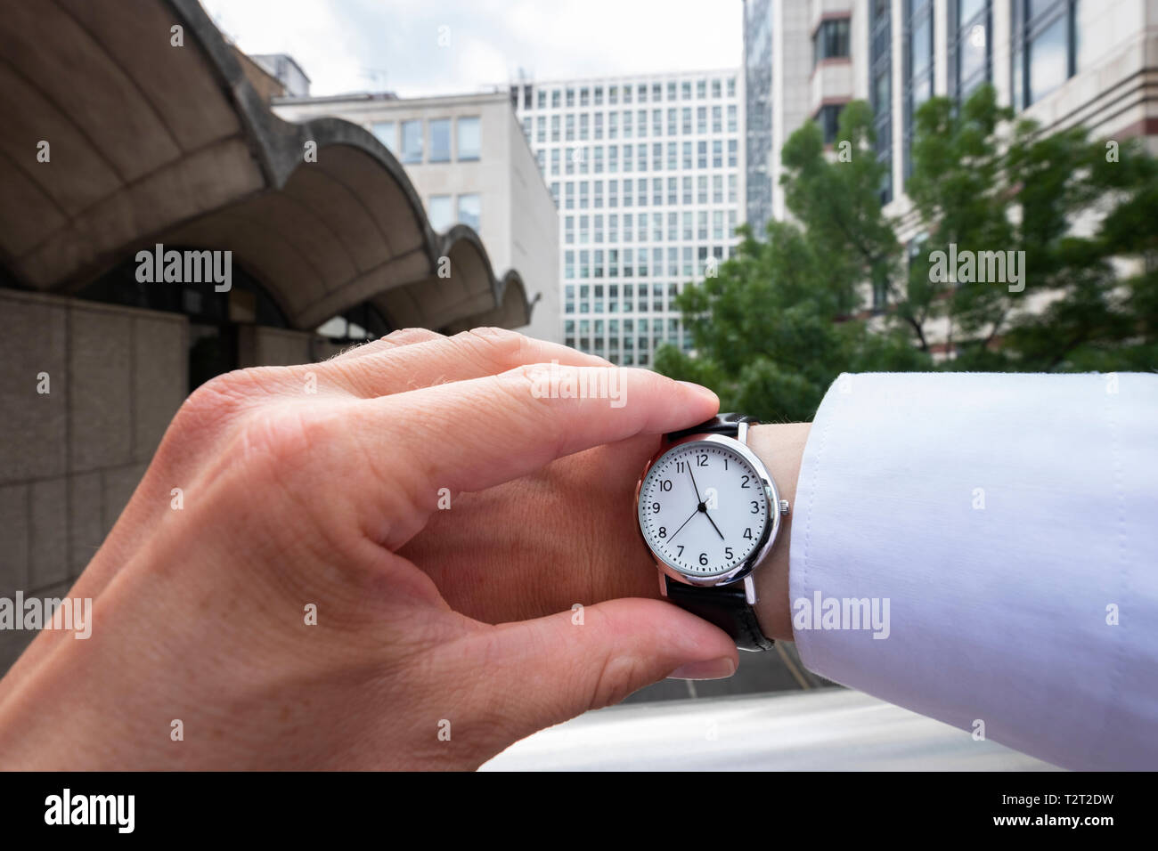 Uomo caucasico indossando un orologio da polso che mostra il tempo 5:00 Foto Stock