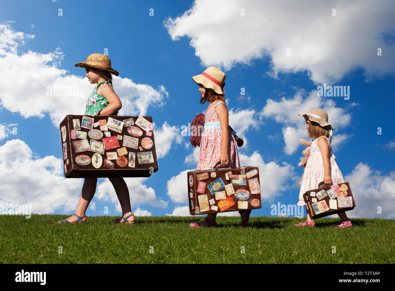 Le tre sorelle holding vintage valigie su una collina Foto Stock