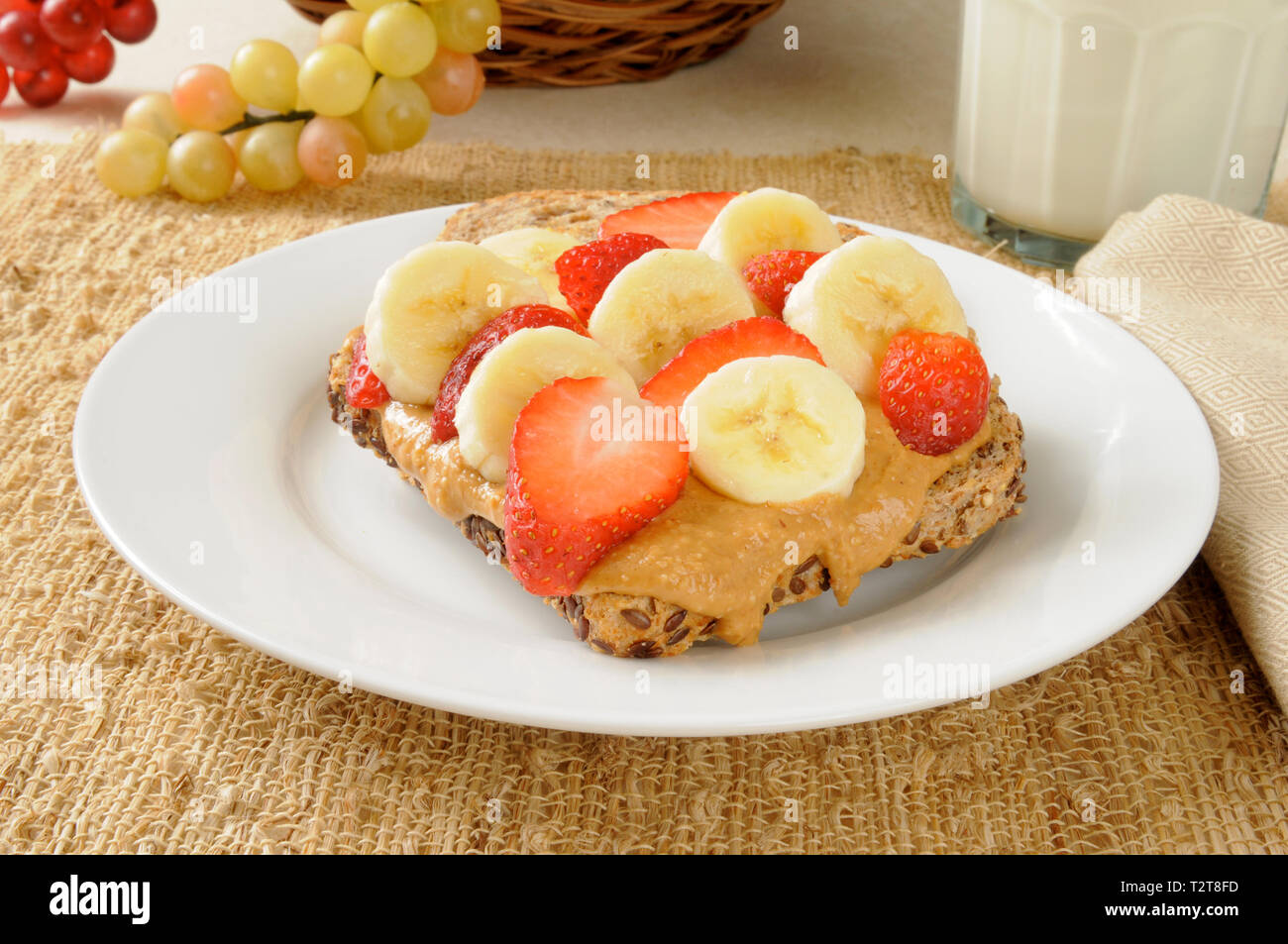 Semi germinati sormontato pane con organici burro di arachidi, Banane e fragole Foto Stock