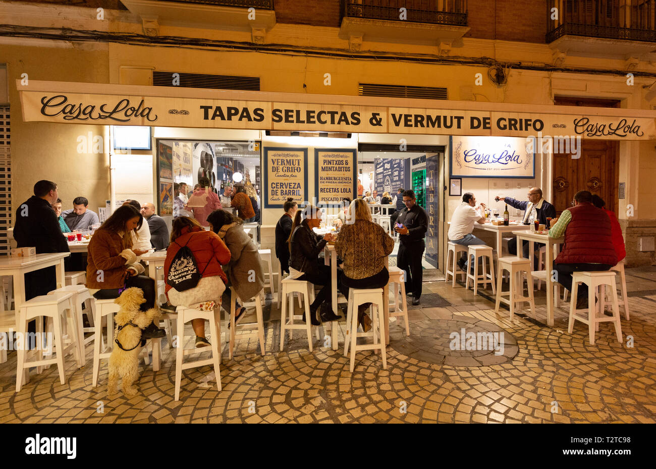 Tapas bar in Spagna - persone sedute a mangiare e bere all'aperto a Casa Lola, un ristorante di tapas e bar di notte, città vecchia di Malaga, Andalusia Spagna Foto Stock