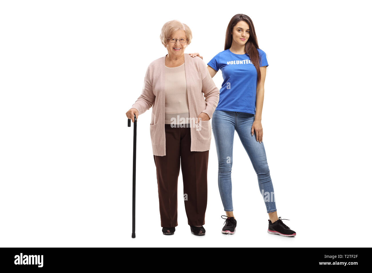 A piena lunghezza Ritratto di una donna anziana con una canna e un giovane volontario femmina isolati su sfondo bianco Foto Stock