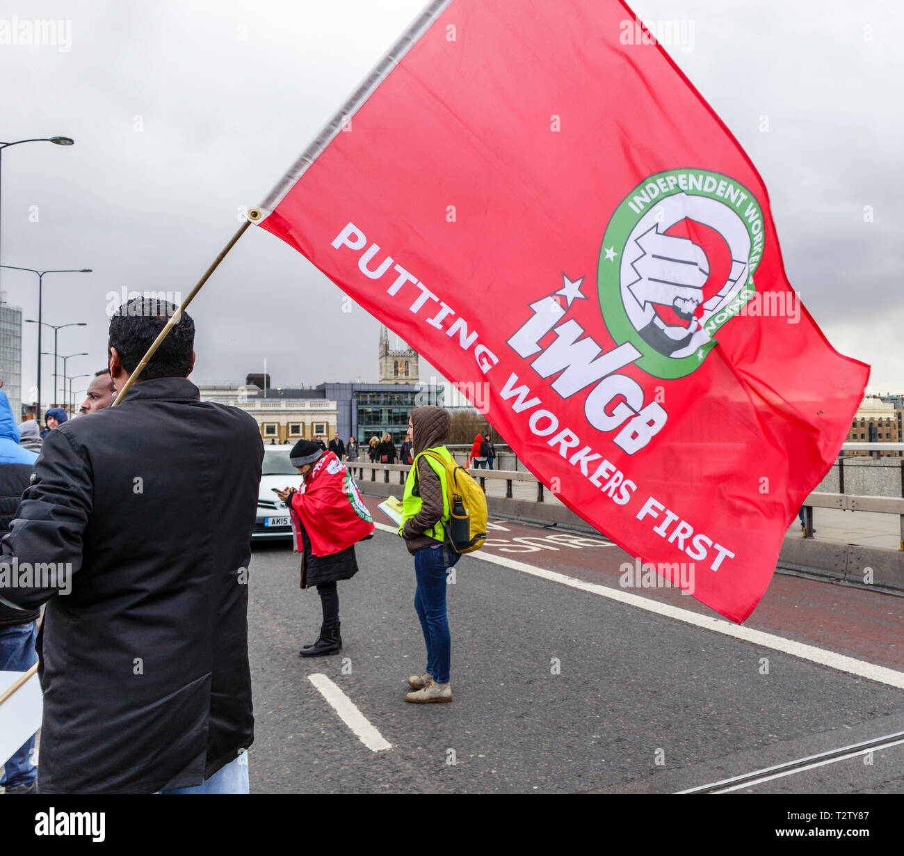 Londra, UK, 04 aprile 2019. I driver di minicab bloccano la strada sul Ponte di Londra per protestare contro il cambiamento di congestione sul noleggio privato radiotaxi. Questo dimostranti trattiene le onde e la bandiera rossa di IWGB (lavoratori indipendenti unione di Gran Bretagna). Credito: Graham Prentice/Alamy Live News Foto Stock