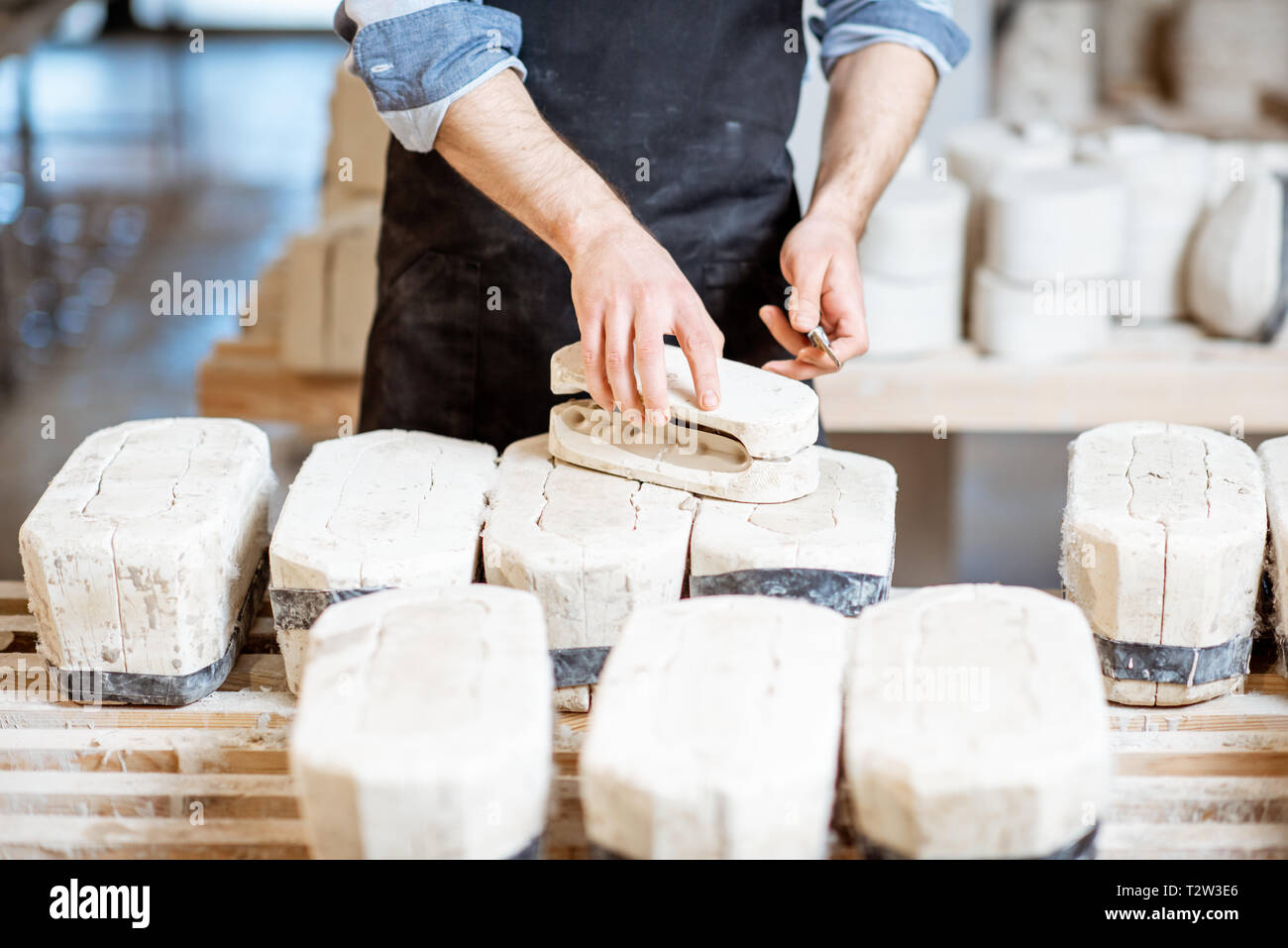 Lavoratore di sesso maschile di ottenere prodotti di argilla dalle forme di gesso alla fabbricazione ceramica, vista da vicino Foto Stock